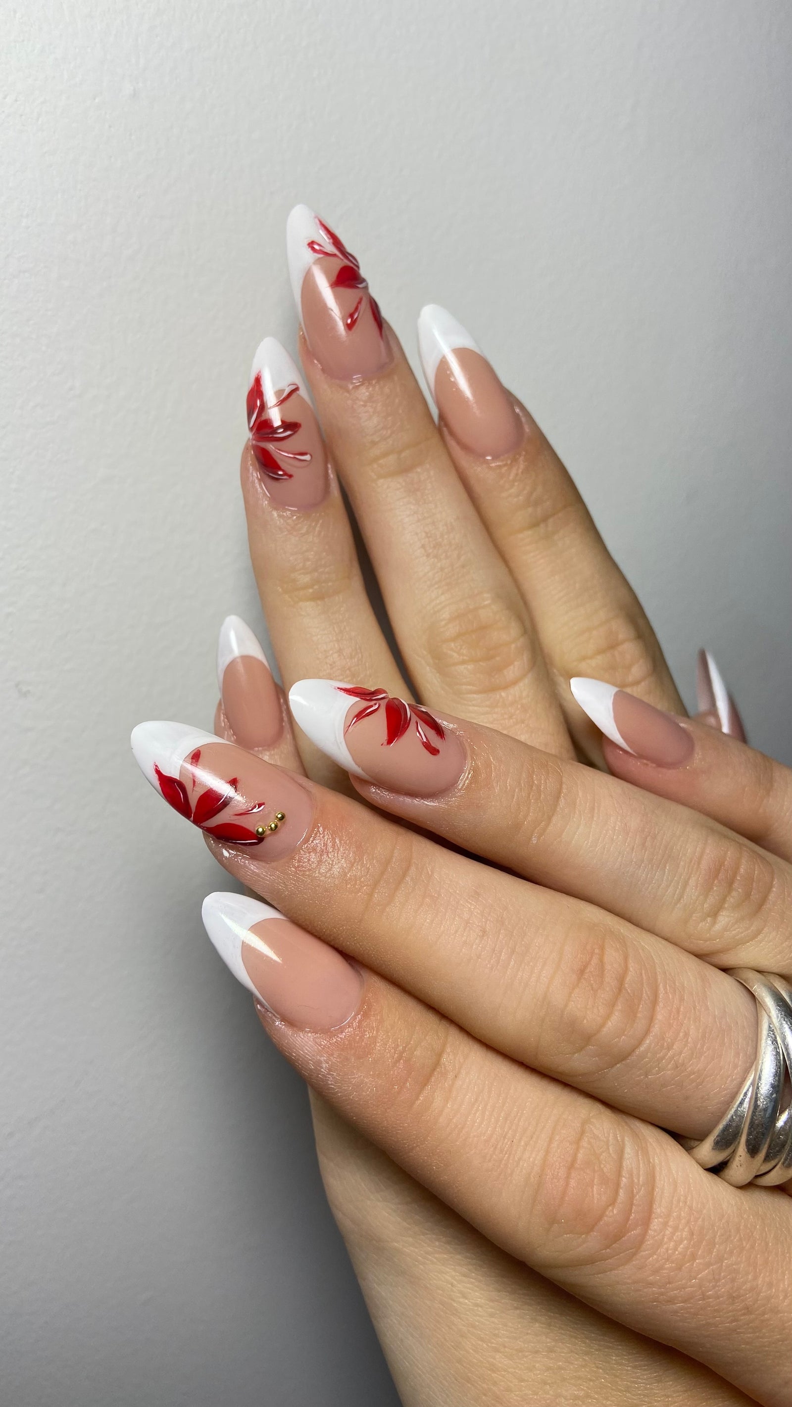 Lange amandelnagels met witte French tips en rode bloemen